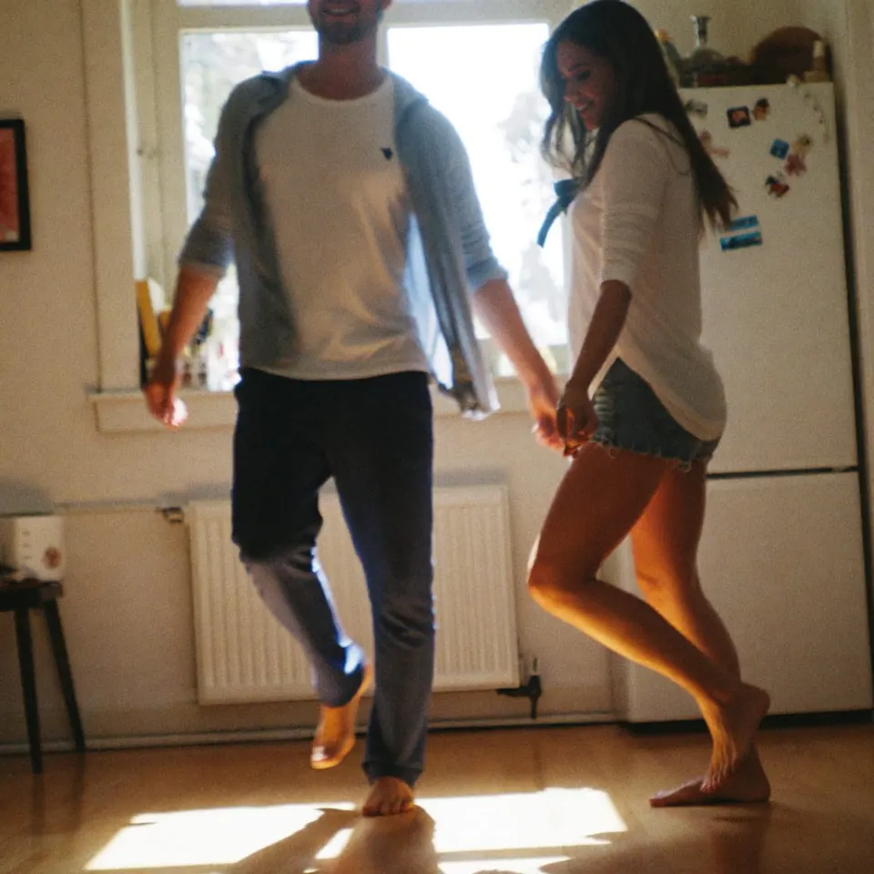 A couple dancing barefoot in a sunlit kitchen on a slow Sunday morning